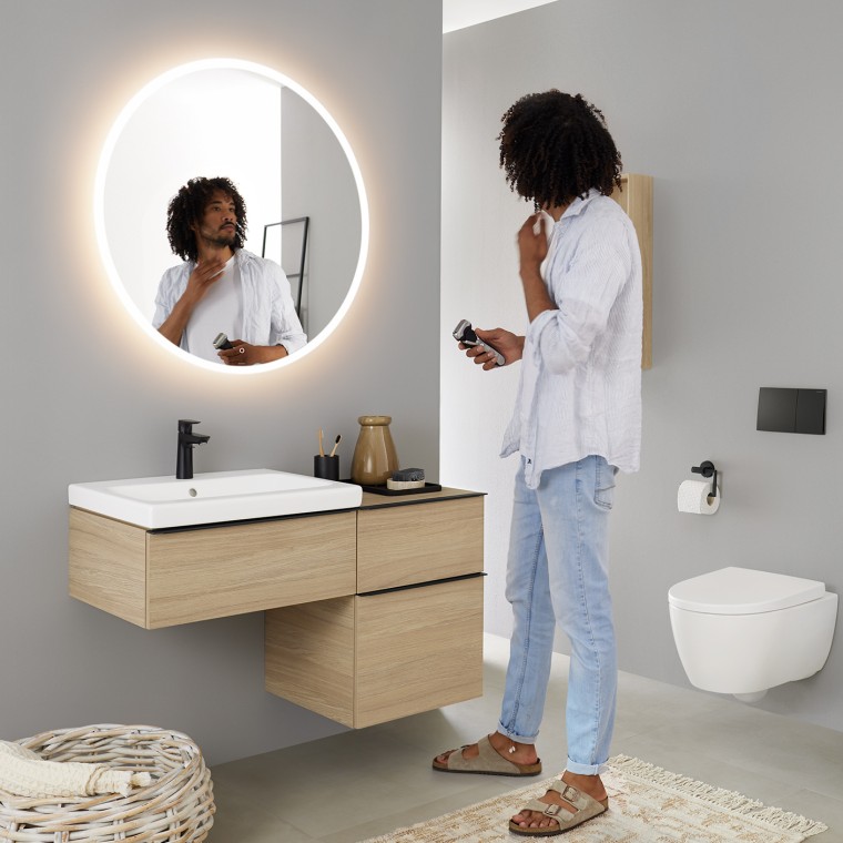 Man looking at himself in a round illuminated Geberit Option mirror Man looking at himself in a round illuminated Geberit Option mirror