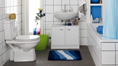 Cluttered bathroom seen before renovation, with floor-standing WC and exposed cistern