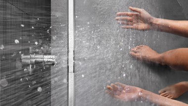 Person showering in a floor-even shower with CleanLine