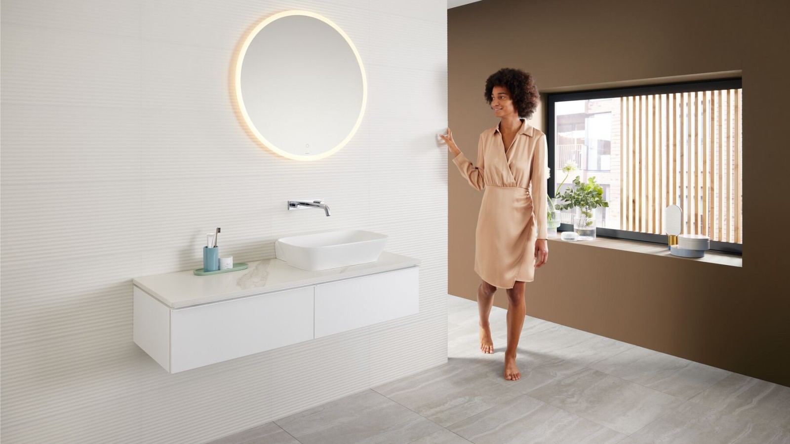 Woman in modern bathroom featuring a brown colour scheme - the latest bathroom colour trend - and a Mix & Match washbasin area combination