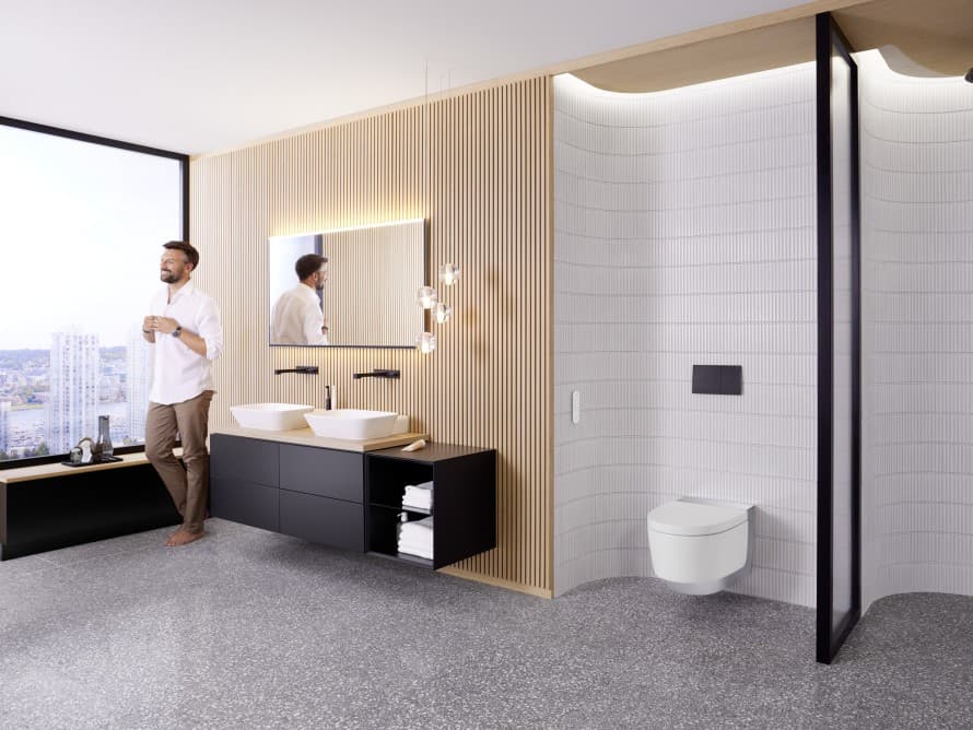 Man in large bathroom with dark furniture and Geberit AquaClean shower toilet Man in large bathroom with dark furniture and Geberit AquaClean shower toilet